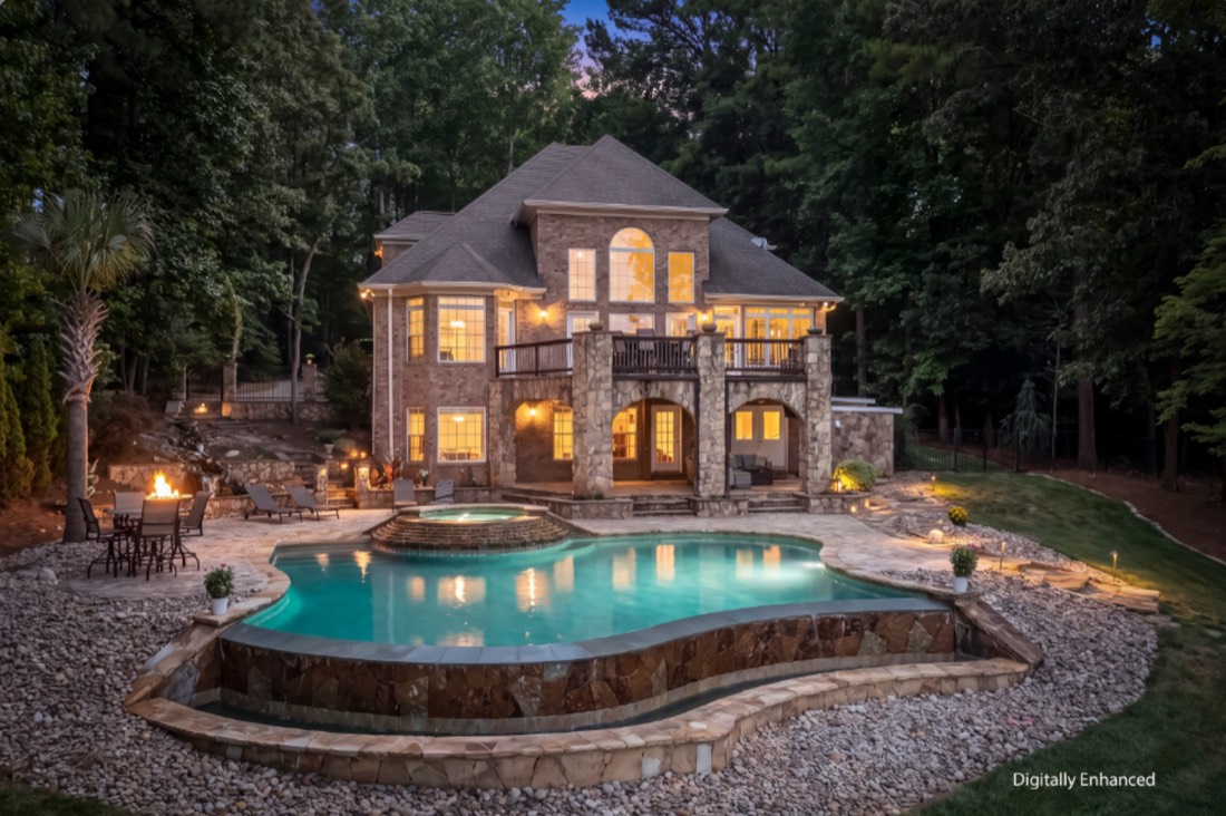 Brick house at twilight, windows lit, pool in the foreground